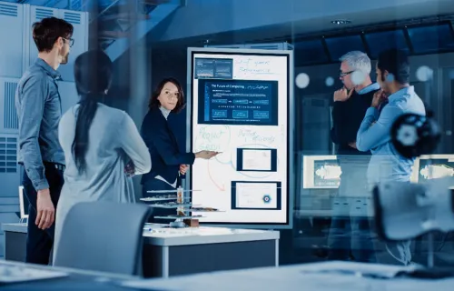 Group of engineers collaborating around a digital board