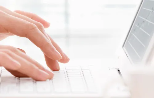 Närbild på händer som skriver på ett vitt tangentbord