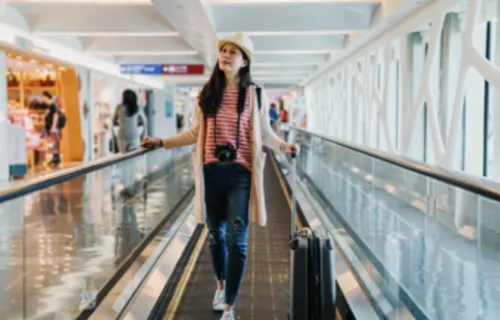 Mujer en el aeropuerto caminando con su equipaje. 