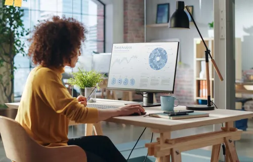 woman sits at desk studying a monitor with data