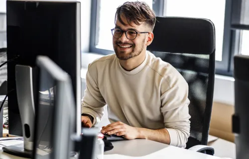 Male professional sat at computer desk and smiling