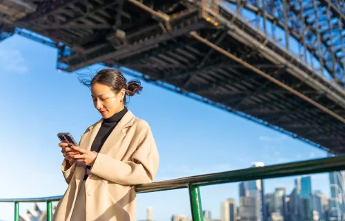 Frau steht auf einer Brücke und schaut auf ihr iphone