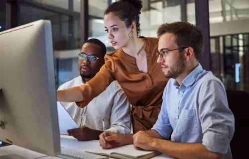 Two men and a woman looking at a monitor