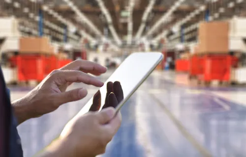 Person mit iPad in der Hand in einer Fabrik stehend