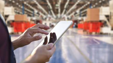 Person mit iPad in der Hand in einer Fabrik stehend