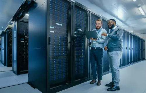 IT Technicians with a laptop running diagnostics in data center with server racks