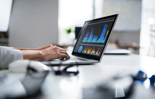 professional on laptop with financial data on screen