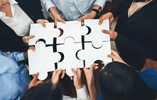 Group of people holding large puzzle pieces together