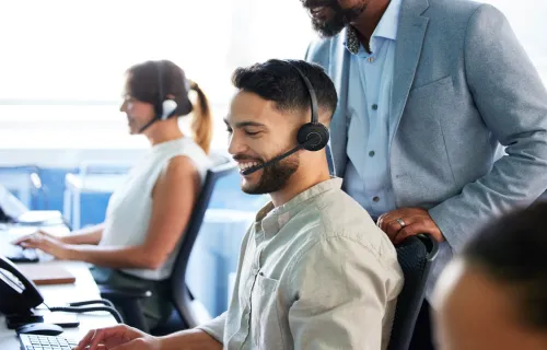 Smiling man in call centre at desk wearing headset