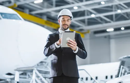 Mann mit Tablet in einer Flugzeugwartungshalle bei Change Management und digitaler Steuerung.