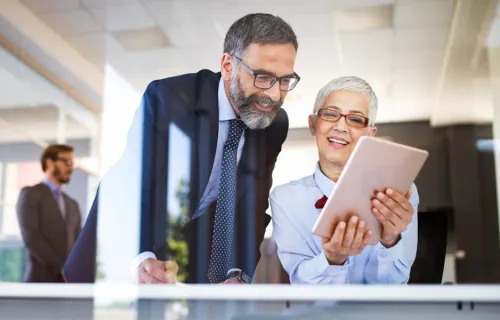Two mature people look at tablet screen 