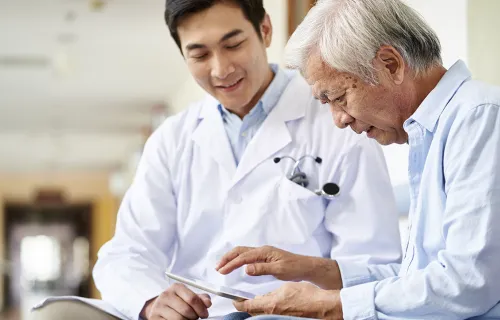 Medical professional looking at tab with elder patient
