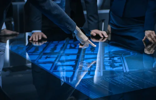 A finger points at a digital map interface on a table