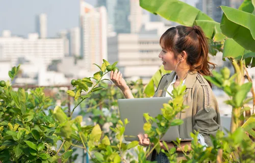 Woman happing looks at the plants holding a laptop