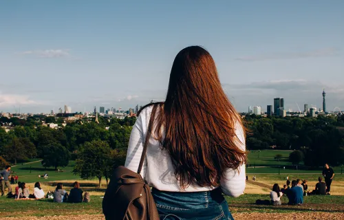 Female in a park looking out to a city skyline 