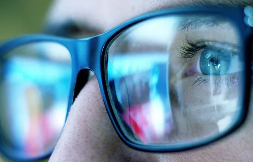 Närbild på glasögon och en person som läser på en skärm 