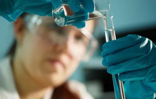 Lab technician pouring sample into test tube 