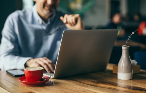 person having coffee while working at laptop