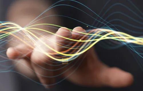 Hand reaching out to touch Quantum computing waves 