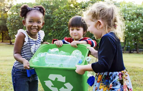 3 small children carrying a recycling bin