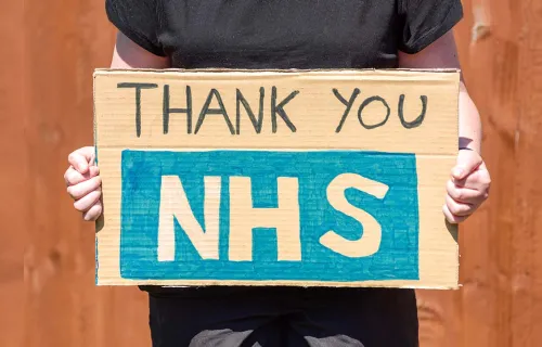 person holding up a hand made sign that says thank you NHS
