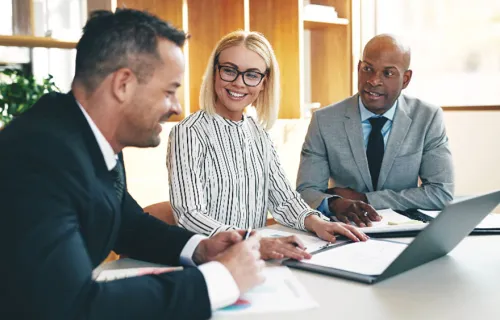 Drei Kollegen sitzen an einem Tisch und freuen sich über Frank Witter als neues Mitglied bei CGI