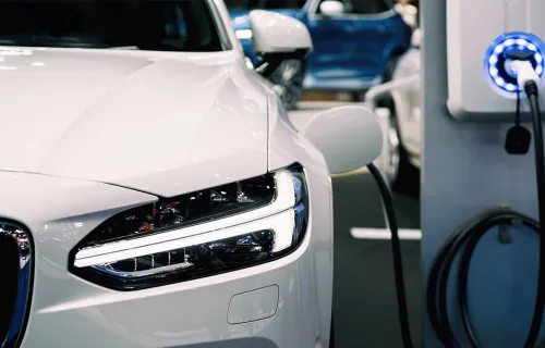Close up view of a car’s headlights while plugged into an electric vehicle charging point.