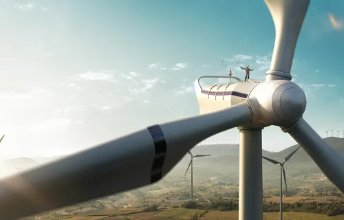 l'homme se tient sur une éolienne avec plus de turbines dans le paysage en arrière-plan