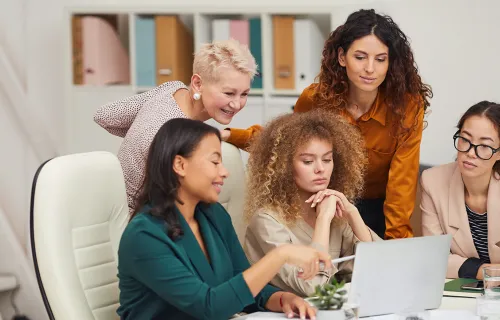 Eine Gruppe von Frauen gucken gemeinsam in einen Laptop