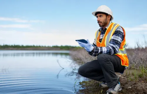 Worker using tablet device by a river bank
