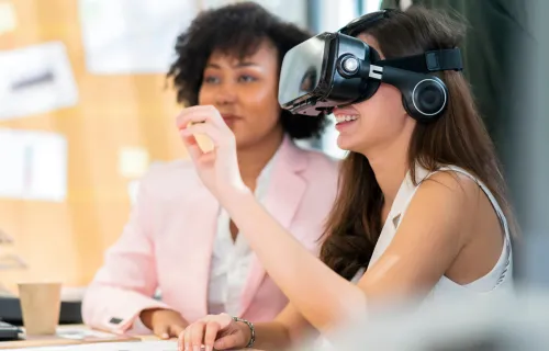 Zwei Frauen sitzen nebeneinander und eine Frau probierte eine VR-Brille aus