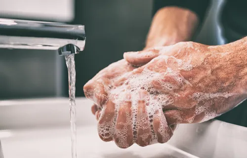 person washing hand with soap under a tap