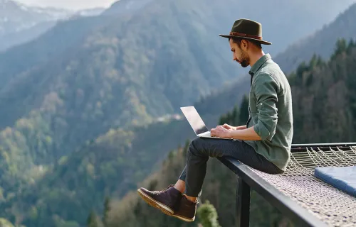 digital nomad using laptop in mountains
