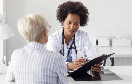 Eine Ärztin hält ein Tablet in der Hand und bespricht etwas mit einer Patientin