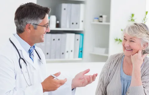 Male Doctor talking with elderly female Patient in Doctors Office