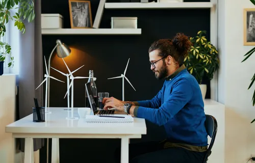man working from home at desk with small model wind turbines