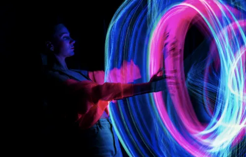 person putting hand through pink and blue light portal