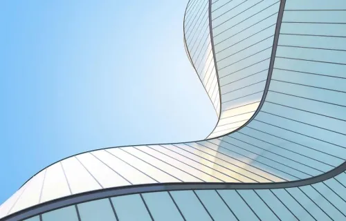 Upwards angle view of an abstract silver wave shape building and blue sky