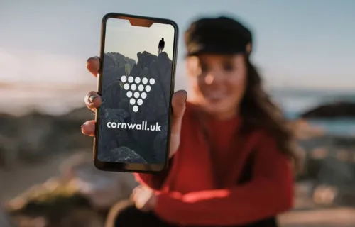woman holding mobile showing cornish ambassador logo