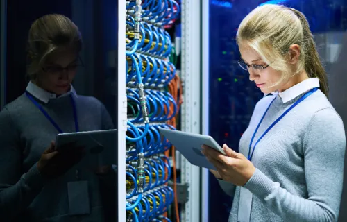  - woman in server room looking at a tablet device