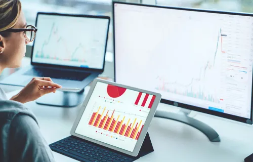 Business person viewing banking trade data on multiple screens