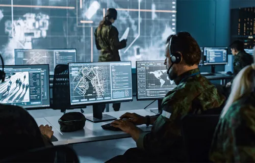 Ein Mann in Uniform sitzt vor dem PC und beschäftigt sich mit Defence & Intelligence