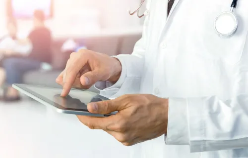 Ein Arzt benutzt sein Tablet, um über die CGI App FindMyPatient Patienteninformation einzusehen