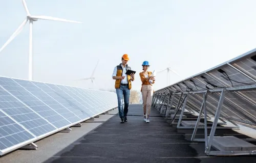 Solar power plant with two engineers walking and examining photovoltaic panels