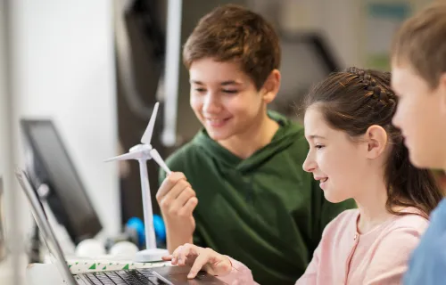 three children playing with laptop and smiling