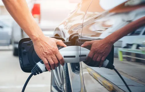 Person holding electric charger into car charging port
