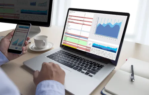 Treasury cybersecurity professional reviewing financial data on laptop and smartphone