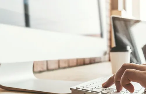 Une main de femme en train d'écrire sur un clavier d'ordinateur