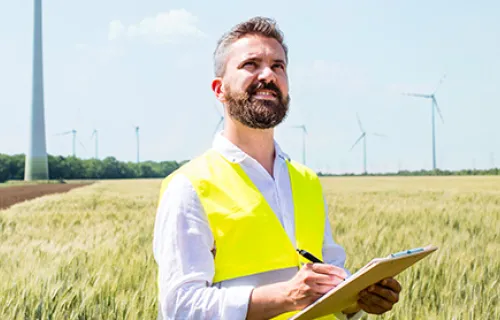 energy and utilities worker in field with wind turbine