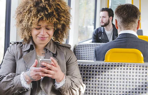 Woman sat on West Midlands Tram looking at her phone